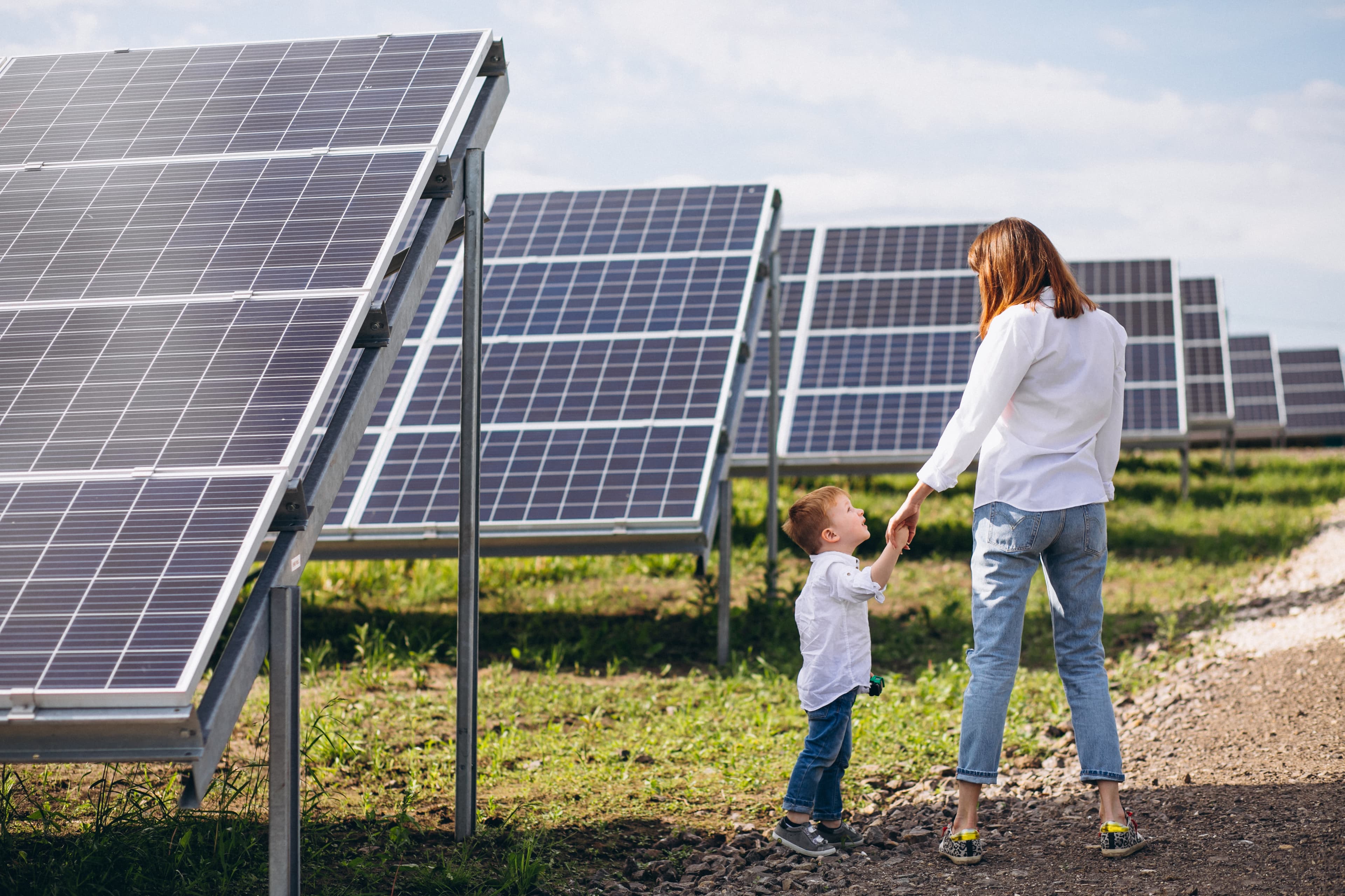 Mãe com uma criança junto a painéis solares, transmitindo segurança e poupança